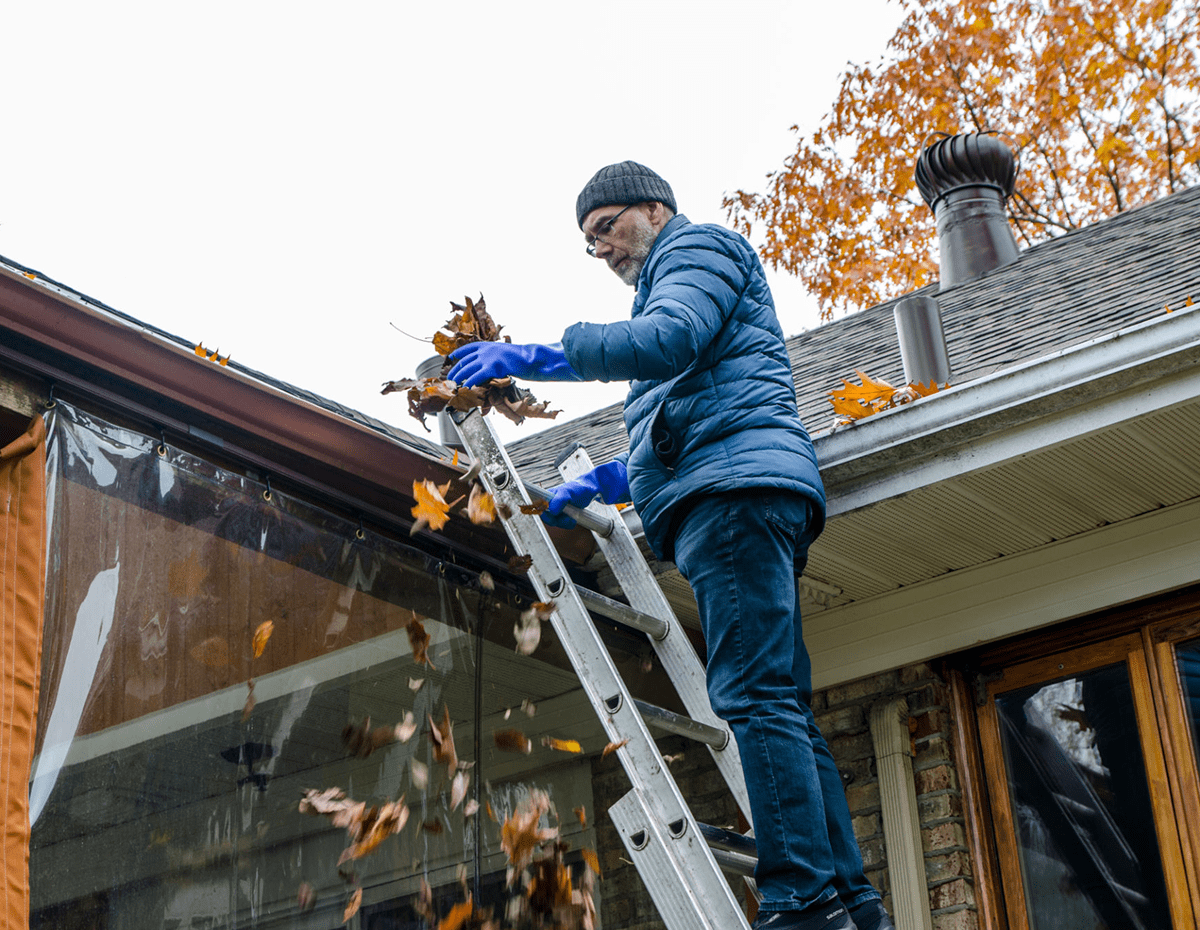 Man cleaning leaves from house gutter