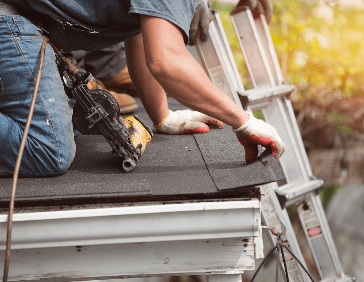Construction worker installing roof shingles